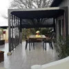Pergola Bioclimatique Alu Anthracite 10,80m² Toit Avec Lames Ovales Alu + 5 Panneaux Moucharabieh + 1 Rideau Gris – HABRITA